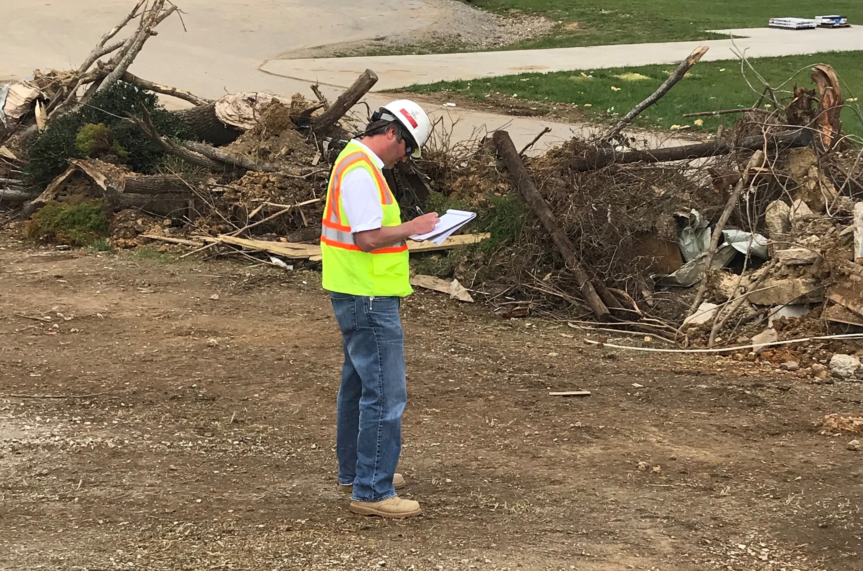 A disaster relief worker taking nots next to debris from a hurricane.